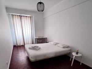 a white bedroom with a bed and a table at Flores Terrace Apartment in Lisbon