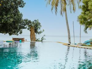 uma piscina com palmeiras e o oceano em Munchies Bungalows em Ban Tai