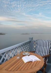 a wooden table with a book and a cup of coffee on a balcony at Akro Luxury Living in Astypalaia Town