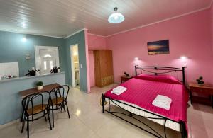ein Schlafzimmer mit einem rosa Bett sowie einem Tisch und Stühlen in der Unterkunft Elena Pool in Agios Georgios