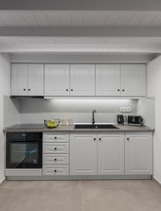 a kitchen with white cabinets and a sink at Akro Astypalea in Astypalaia Town