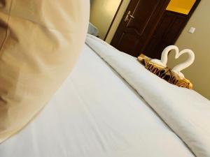 un letto con lenzuola bianche e due cuscini con cuori di ISIS Hôtel a Yaoundé