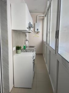 una piccola cucina con armadi bianchi e lavandino di Fondaco House a Napoli