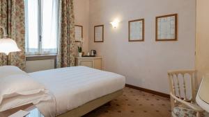 a hotel room with a bed, chair, and window at PHI Hotel Canalgrande in Modena