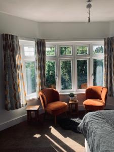 a bedroom with two chairs and two windows at Elmside, The Luxury New Forest Retreat in Southampton