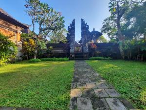un giardino con sentiero in pietra di fronte a un edificio di Sahadewa House ad Ubud