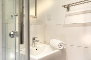 a white bathroom with a sink and a shower at T3 Budget Zwickau in Zwickau
