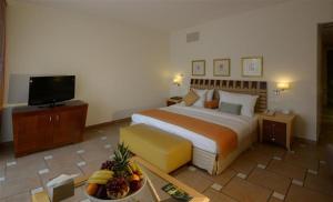 Seashell Julai'a Hotel & Resort Family resort في القليعة: غرفة في الفندق بها سرير ووعاء من الفواكه