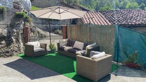 Llamoso的住宿－Casa Rural La Corrada，庭院配有两把椅子和一把遮阳伞