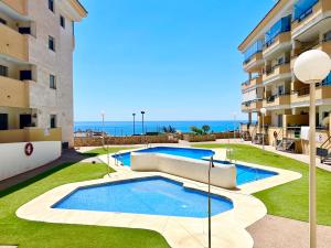 ein Schwimmbad in der Mitte eines Gebäudes mit dem Ozean im Hintergrund in der Unterkunft Apartment Sea Breeze – Apartamento Brisas del Mar in Benalmádena