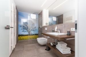 a bathroom with a toilet and a sink with a tree mural at cityhotel in Bocholt