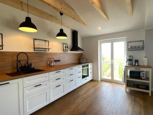 uma cozinha com armários brancos, pisos em madeira e uma janela em Ferienwohnung Watt'n Ausblick em Simonsberg
