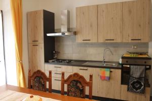 uma cozinha com armários de madeira, um lavatório e um fogão em casa vacanze Nonna Nunzia em Bosa