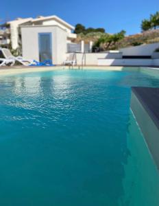 a swimming pool with blue water in front of a house at Valenti rooms & relax in Villaggio Mosè