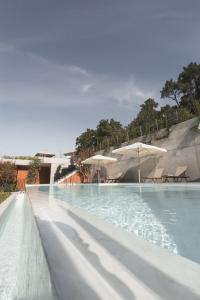 a swimming pool with two umbrellas and a swimming pool at Atmos Hotel Boutique in Outes