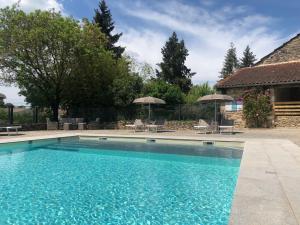 a swimming pool with chairs and umbrellas next to a house at Domaine de Monplaisir in Caylus