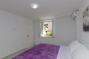 Dormitorio blanco con cama morada y ventana en Apartments Fortinia Dubrovnik- FREE PARKING, en Dubrovnik