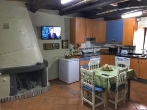 a kitchen with a table and a fireplace with a tv at Casa La Rueda in Ponferrada