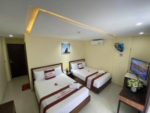 a hotel room with two beds and a television at New Tourane Hotel in Da Nang