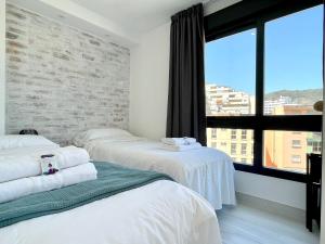 2 camas en una habitación con una pared de ladrillo en Modern Place City & Beachlife in heart of Torremolinos by Solrentspain, en Torremolinos