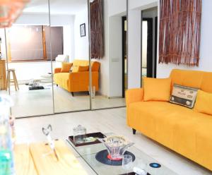 sala de estar con sofás naranjas y mesa de cristal en City Park Apartment, en Constanţa