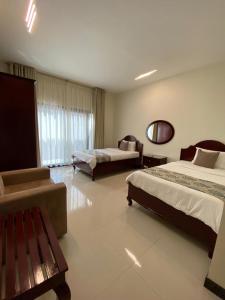 ALZumorod Luxury Villa في Ma‘ābīlah: غرفه فندقيه سريرين ومقعد