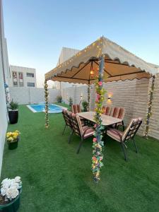 Ma‘ābīlahにあるALZumorod Luxury Villaの芝生の上の傘下のテーブルと椅子