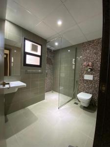 y baño con ducha, aseo y lavamanos. en ALZumorod Luxury Villa, en Ma‘ābīlah