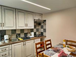 a kitchen with white cabinets and a table with chairs at The Stone House in Kalabaka