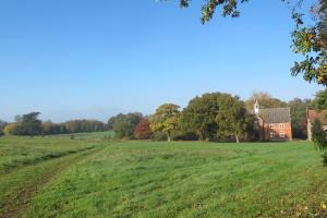 an open field with a house in the background at Spixworth Hall Cottages in Spixworth