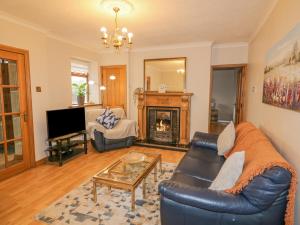 sala de estar con sofá de cuero y chimenea en Annie's Place, en Newry
