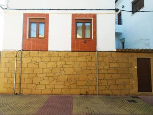 a building behind a brick wall with two windows at El Rincón de Pilar in Casalarreina