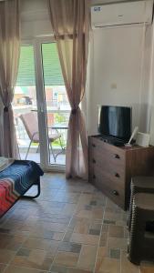 a living room with a tv on a dresser with a window at Nea Kalikratia sea view in Nea Kallikrateia