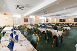 un salón de banquetes con mesas y sillas blancas en The Crown Hotel en Weymouth