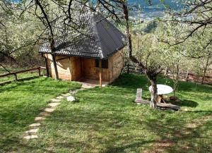 a small wooden cabin in a field with a tree at Bungalows Old Town in Visoko