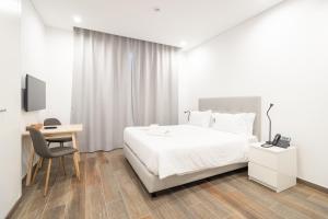 a bedroom with a bed and a desk and a tv at Roots Hotel in Faro