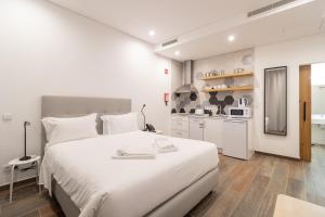a white bedroom with a large bed and a kitchen at Roots Hotel in Faro