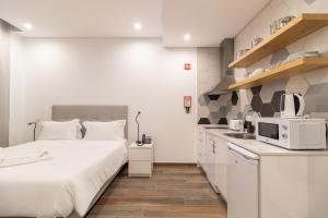 a small white kitchen with a bed and a microwave at Roots Hotel in Faro