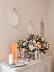 una mesa con un jarrón de flores y dos espejos en Villa Diletta b&b, en Forte dei Marmi