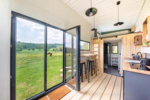 cocina abierta y sala de estar con puertas correderas de cristal en Tiny House Centre équestre - 35 mins de Paris, en Chambly