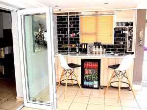 una cocina con una barra con 2 sillas blancas en Comfort e Casa en Kempton Park