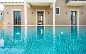 a swimming pool in front of a house with blue water at Luxury Villa Chrisi in Svoronata