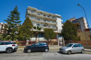 tres autos estacionados en un estacionamiento frente a un edificio en B&B CasaBuddace, en Messina