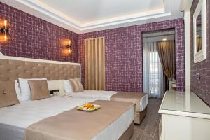 um quarto de hotel com duas camas e azulejos roxos em THE LEA HOTELS & SUITE em Didim