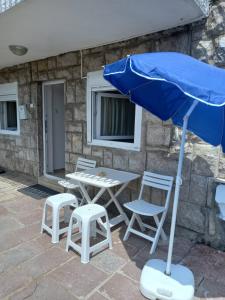 einen Tisch, Stühle und einen Regenschirm auf einer Terrasse in der Unterkunft Apartman Dardic in Herceg-Novi