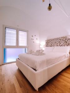 um quarto branco com uma grande cama branca e uma janela em Appartamento elegante alle Due Torri by Wonderful Italy em Bolonha