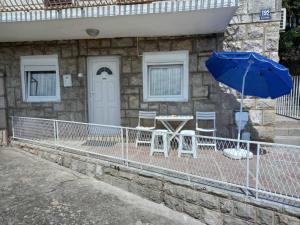 eine Terrasse mit einem Tisch und einem blauen Sonnenschirm in der Unterkunft Apartman Dardic in Herceg-Novi