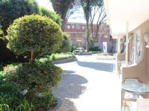 un patio con un árbol, una mesa y arbustos en Comfort e Casa en Kempton Park