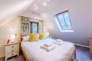a bedroom with a large white bed with yellow pillows at The Nest at Robins Roost in Little Rissington