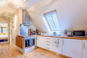 a kitchen with white cabinets and a sink and a window at The Nest at Robins Roost in Little Rissington